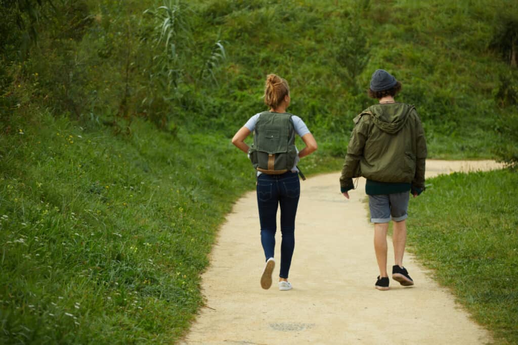 man-and-woman-walking-side-by-side-casually-down-trail