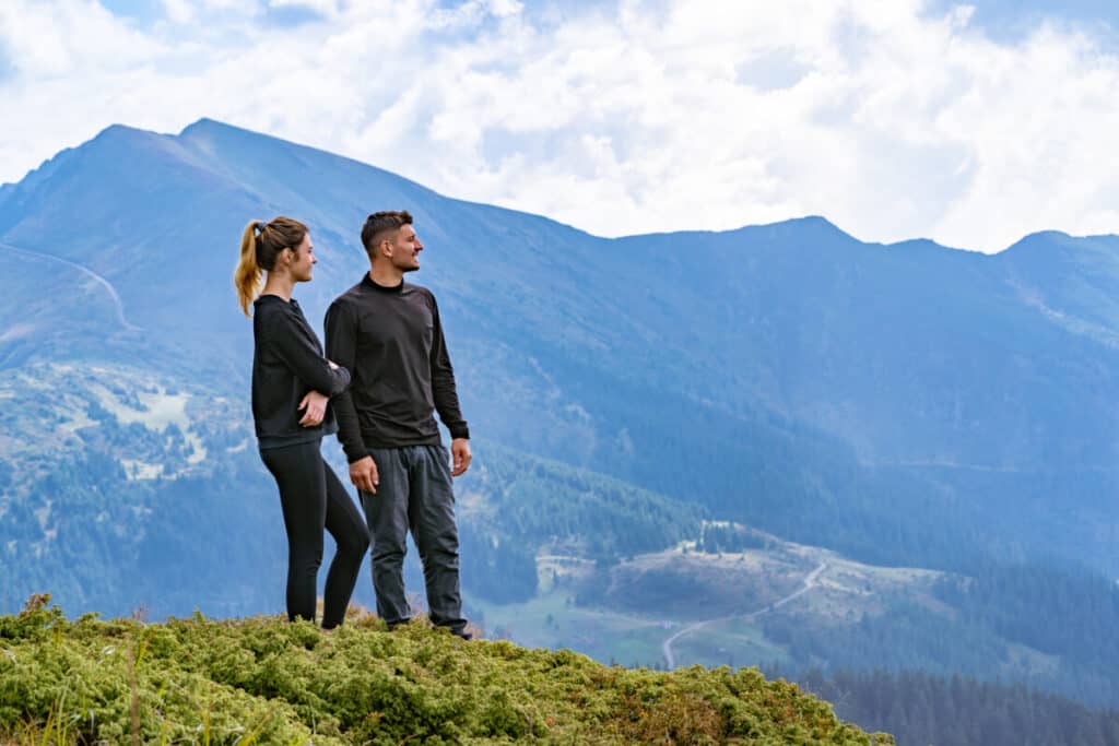 man-and-woman-looking-off-edge-of-high-mountain-vista