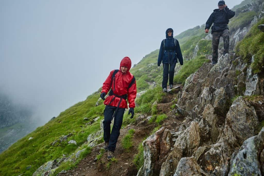 hikers walking down a dangerous mountain trail in the rain.