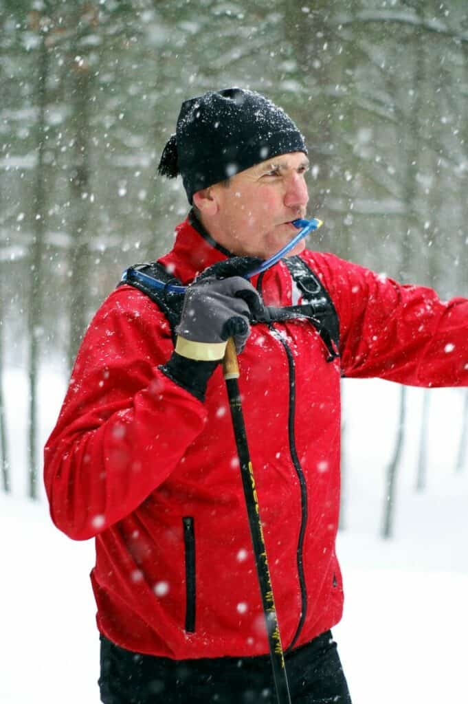 guy using a hydration bladder to drink with poles