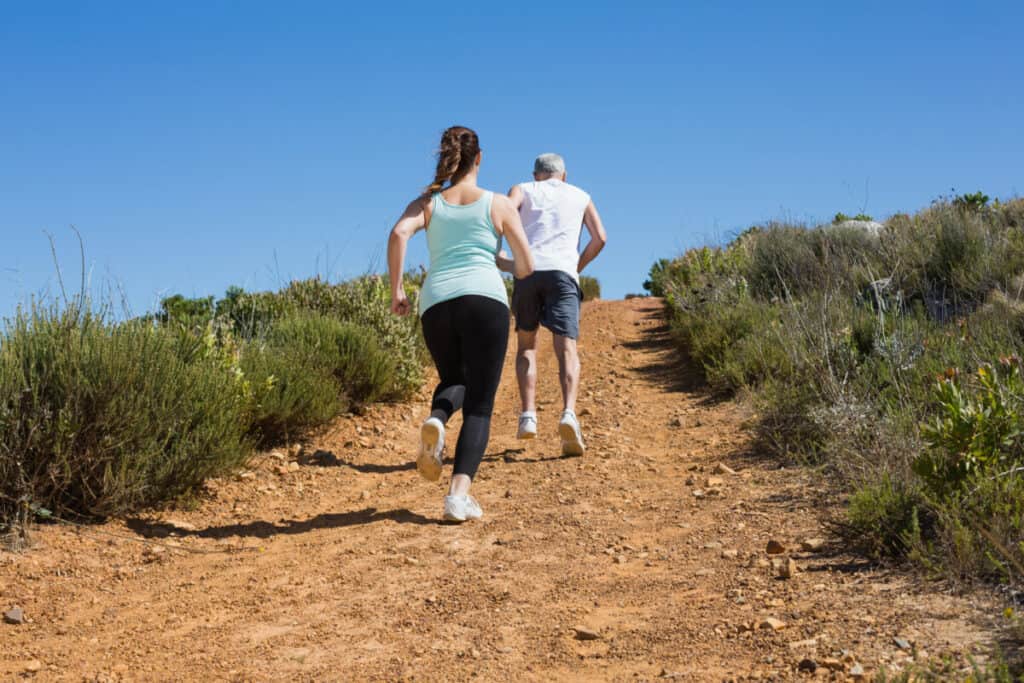 couple running up steep mountain trail