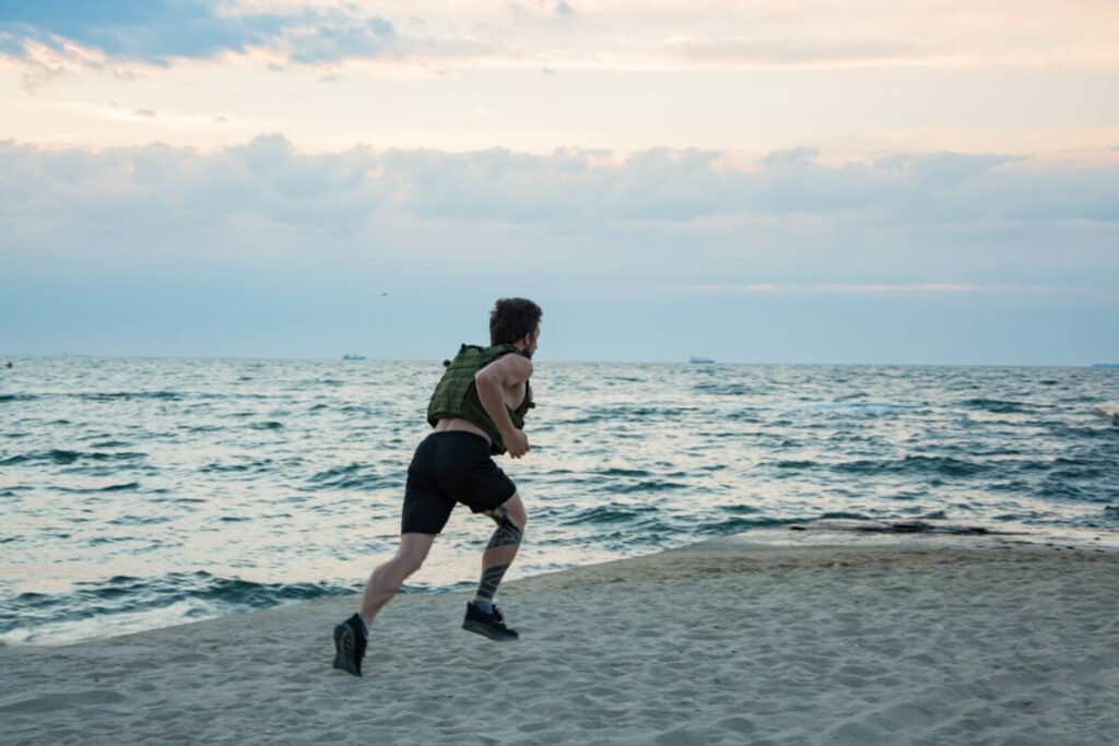man running on beach with weighted vest